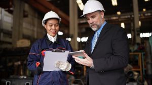 Profissionais registrando relatório de manutenção preventiva com checklist e tablet em ambiente industrial.